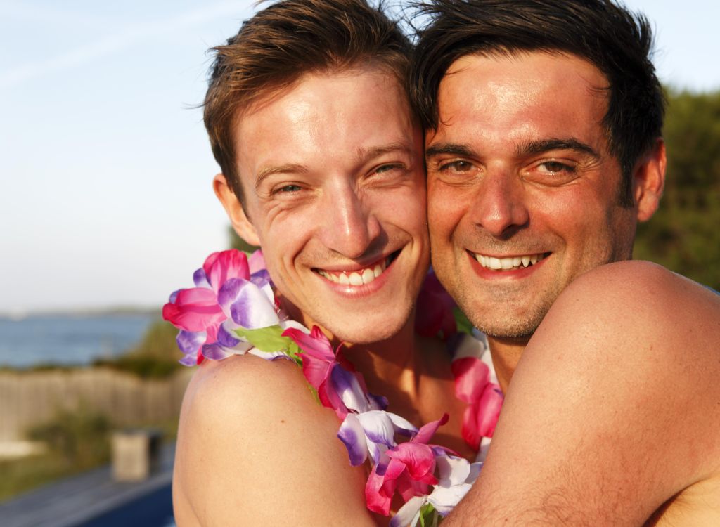 Two men embracing outdoors, one wearing lei