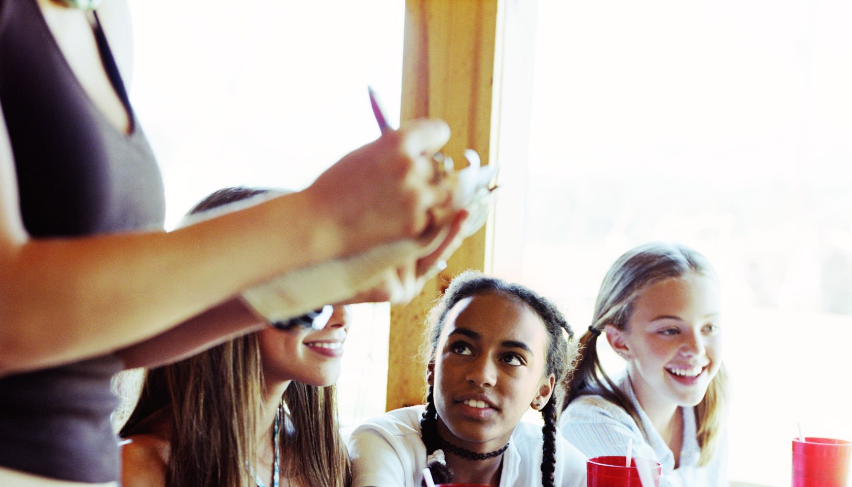 Teenage girls (14-16) giving waitress order in diner