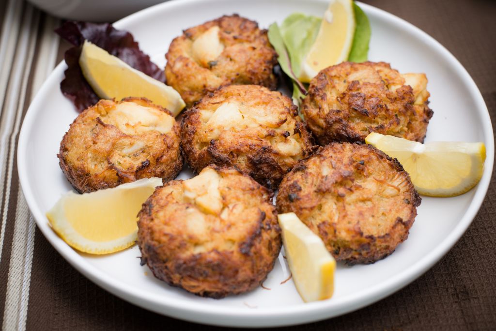 Crab cakes and lemon wedges on plate on table cloth