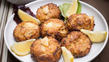 Crab cakes and lemon wedges on plate on table cloth