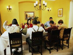 Family saying grace at dinner table