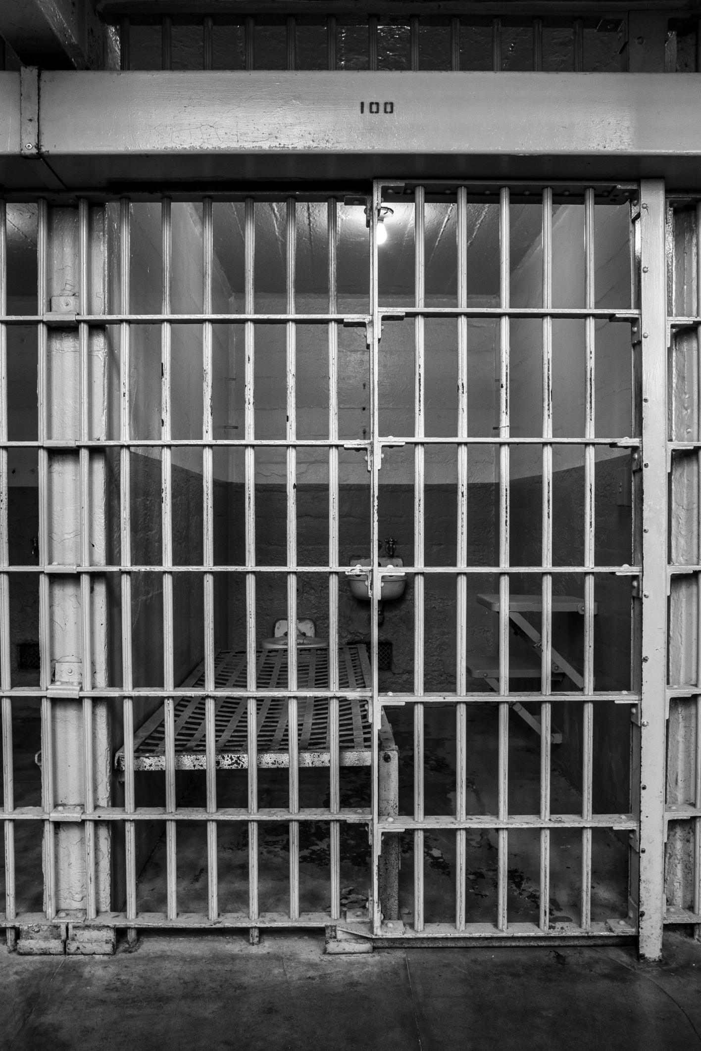 Empty Bed In Illuminated Prison Cell