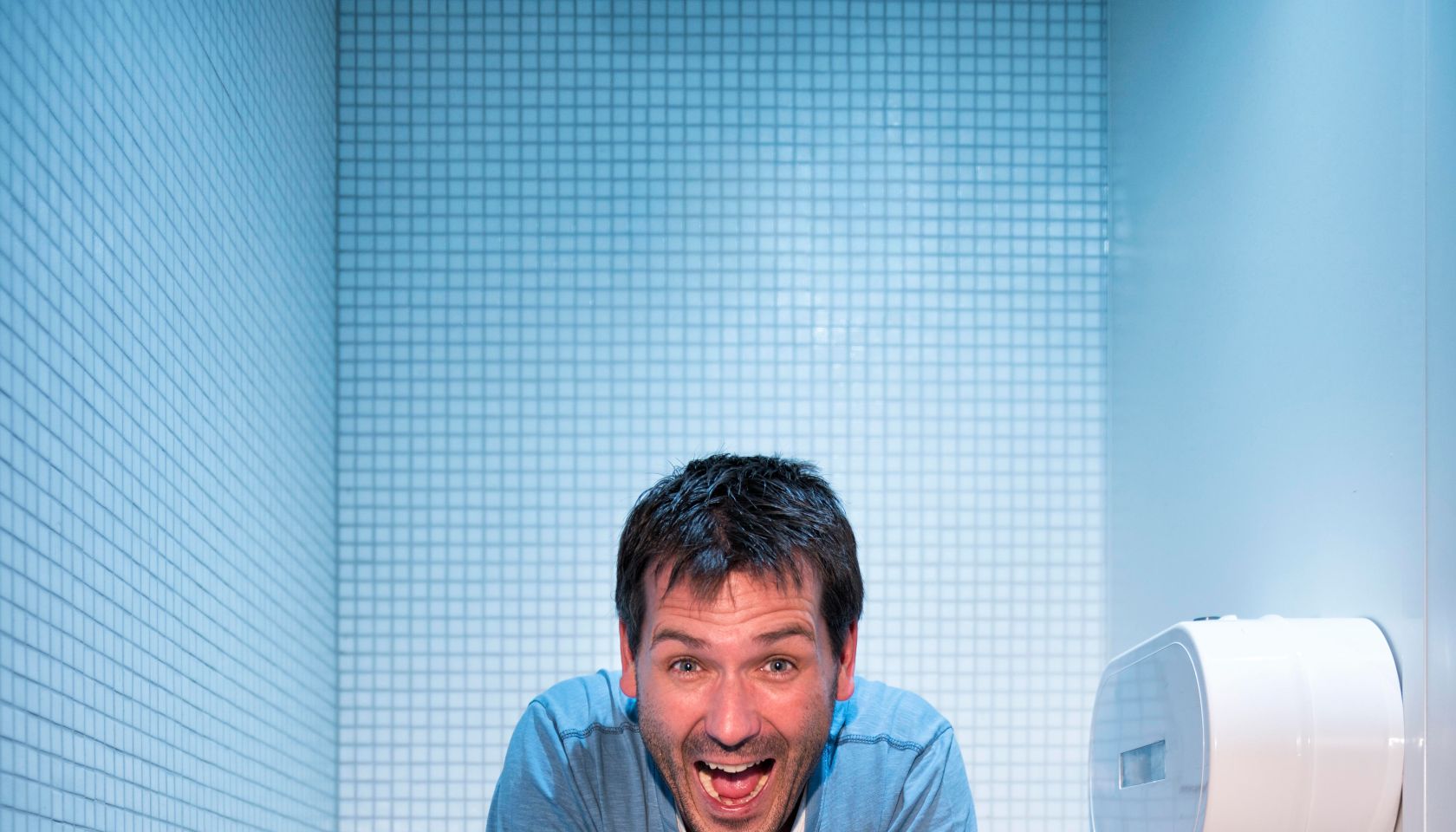 happy man sitting in public restroom