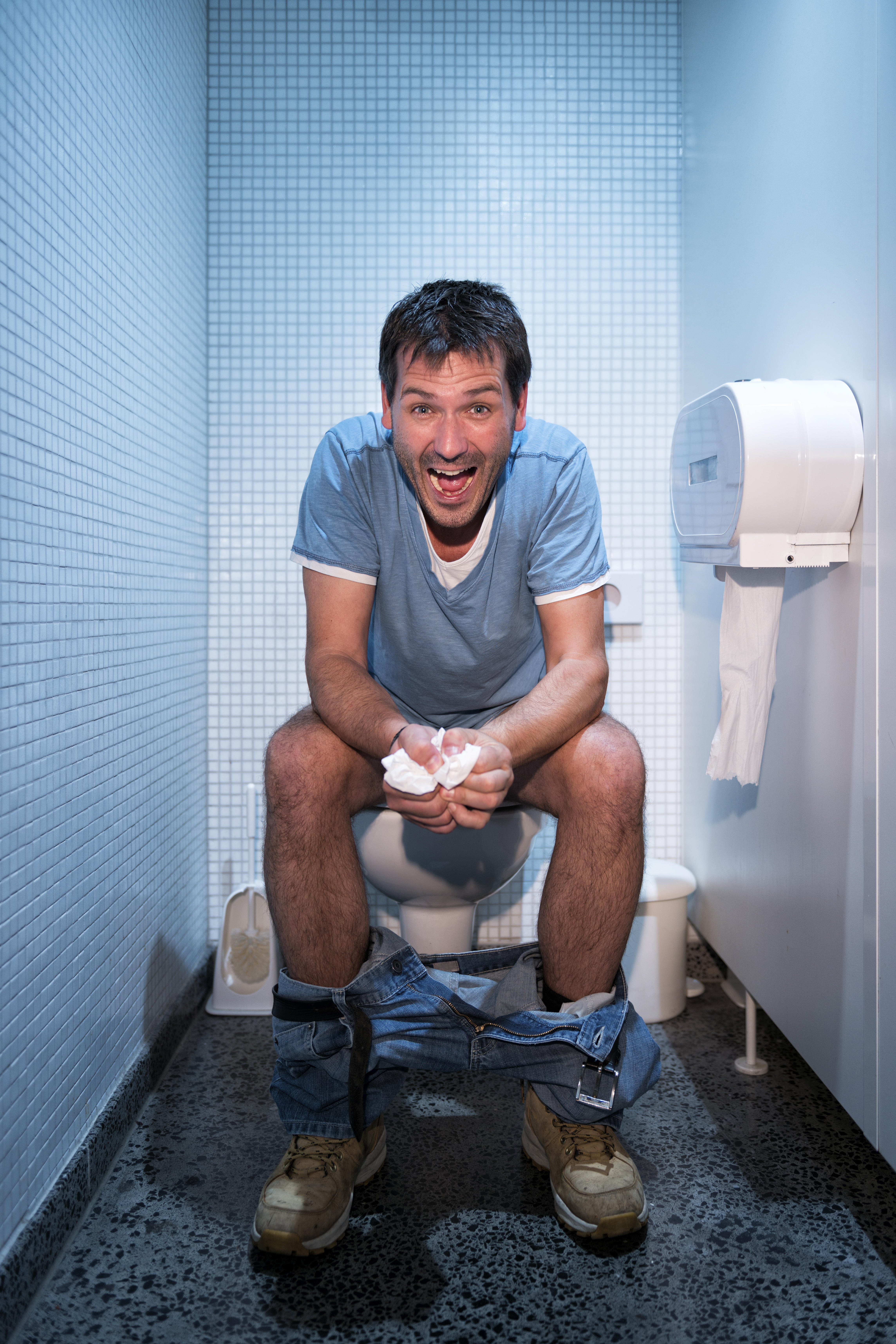 happy man sitting in public restroom