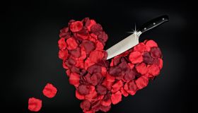 Red rose petals in heart shape with large knife