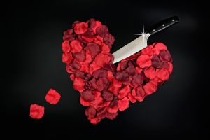 Red rose petals in heart shape with large knife