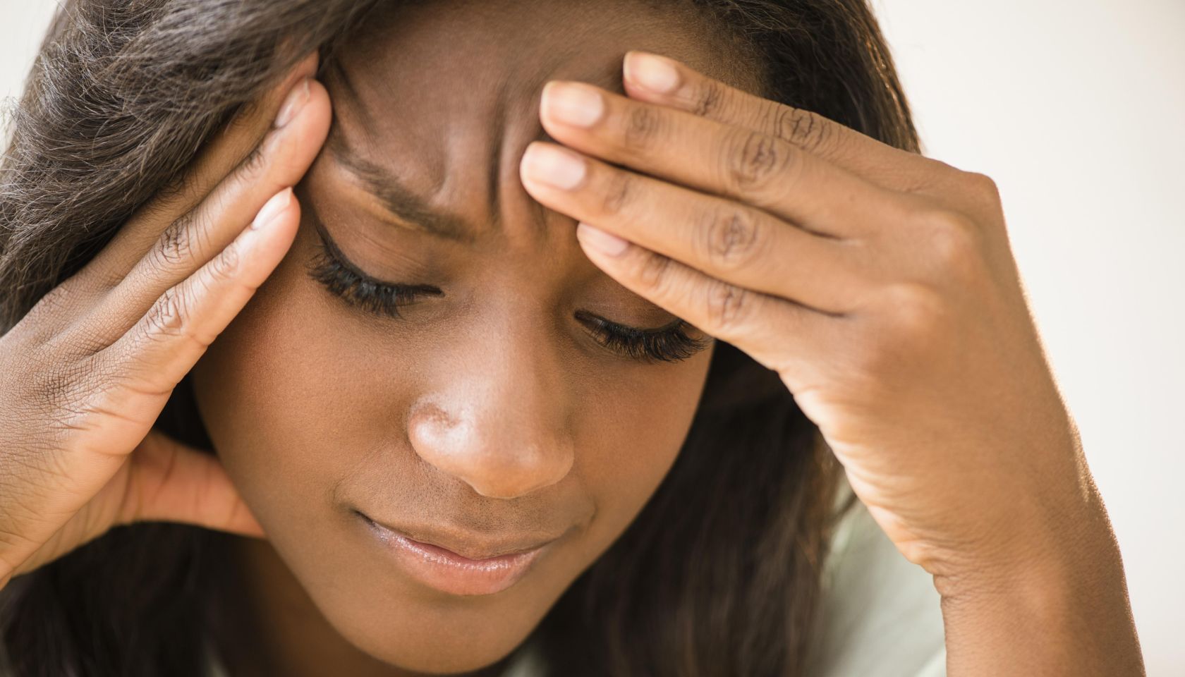 Black woman frowning with head in hands