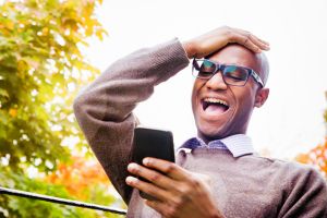 Mature man laughs out loud at story on mobile phone