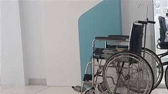 Empty Wheelchair In Corridor At Hospital