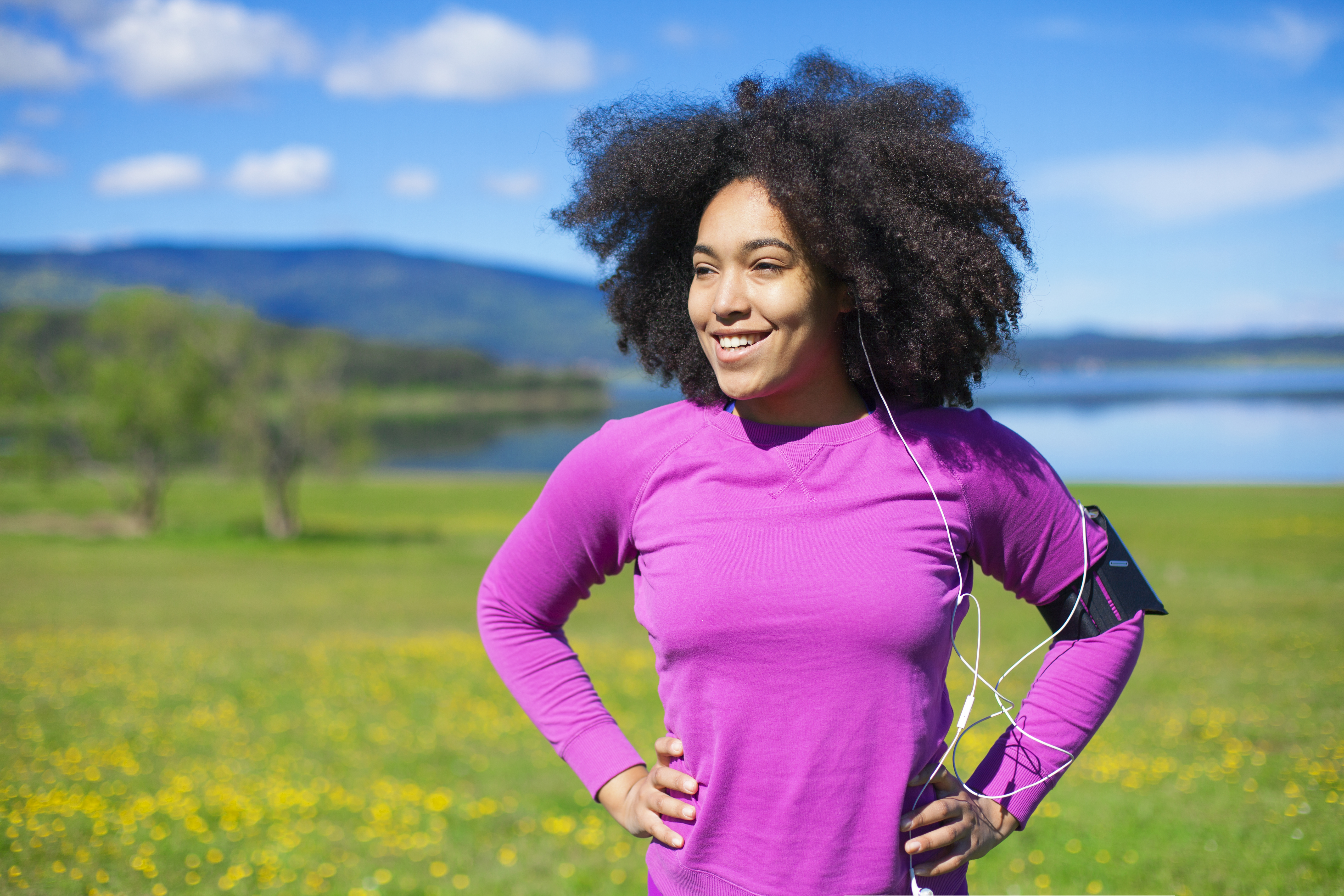 Woman relaxing from exercising in nature, wearing smart technology