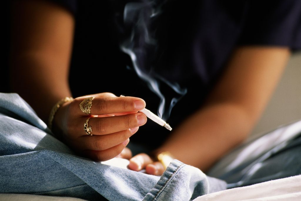 Teenager (16-18) smoking hand rolled cigarette