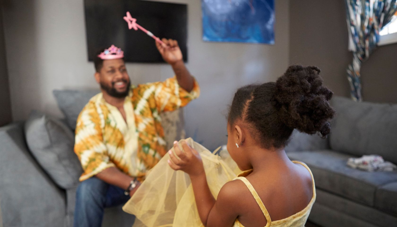 Man casting spell on daughter in fairy costume in living room