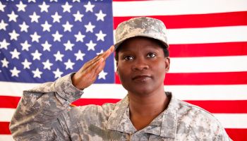 African descent military woman salutes American flag.
