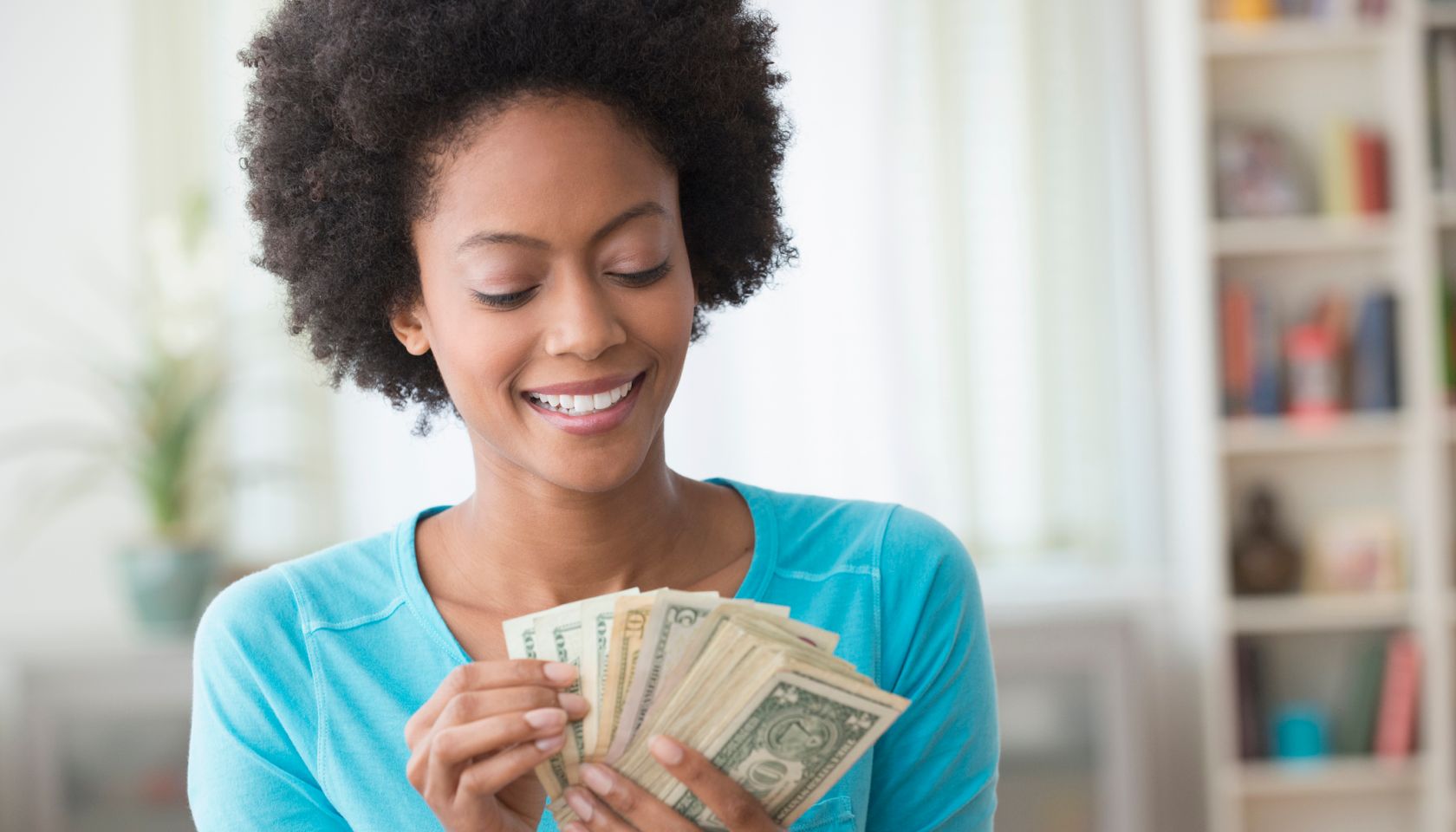 African American woman counting money in living room