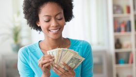 African American woman counting money in living room