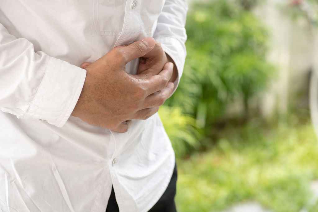 Businessman holding his stomach in pain with stomachache or indigestion