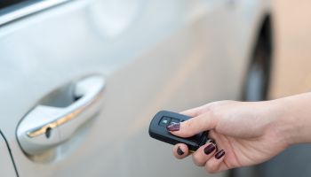 Car remote on hand, pressing button to unlock a car