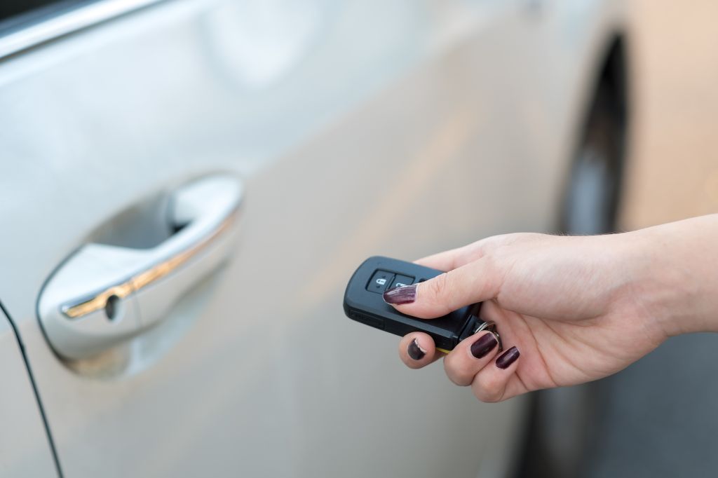 Car remote on hand, pressing button to unlock a car