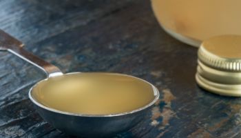Close-Up Of Apple Cider Vinegar In Tablespoon On Wooden Table