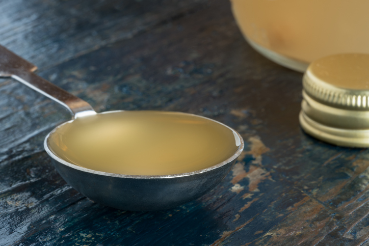 Close-Up Of Apple Cider Vinegar In Tablespoon On Wooden Table