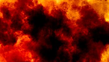 Explosion by an impact of a cloud of particles of powder and smoke of color orange and yellow on a black background.