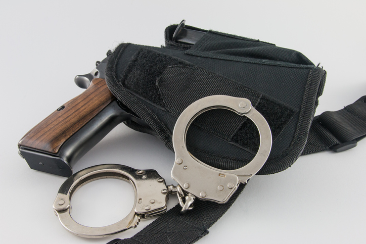 High Angle View Of Handcuffs With Gun On White Background