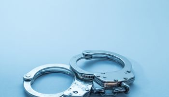Close-Up Of Handcuffs Over Blue Background