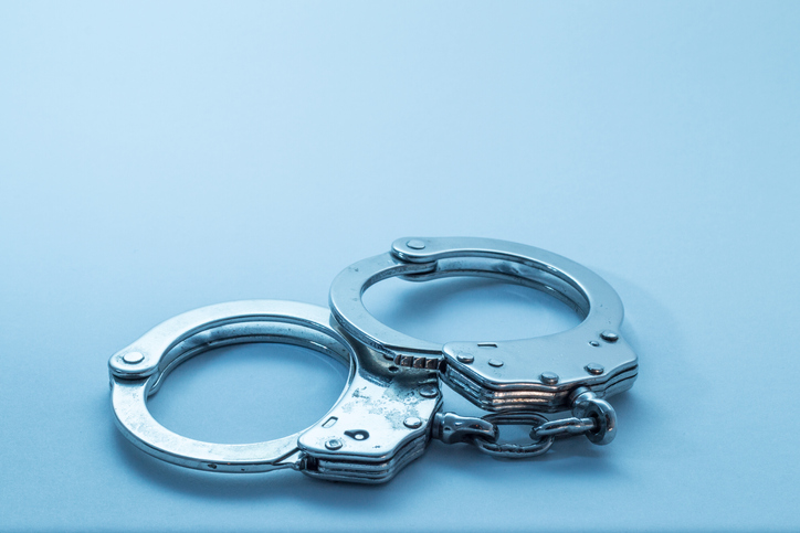 Close-Up Of Handcuffs Over Blue Background