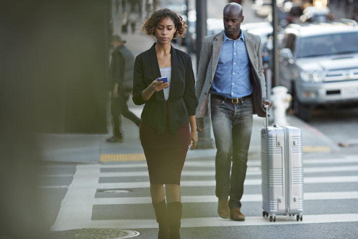 Businesswoman checking smartphone while walking on pedestrian crossing