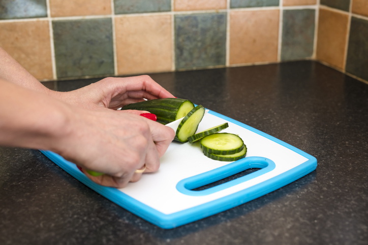 Woman's hands cutting fresh organic cucumber