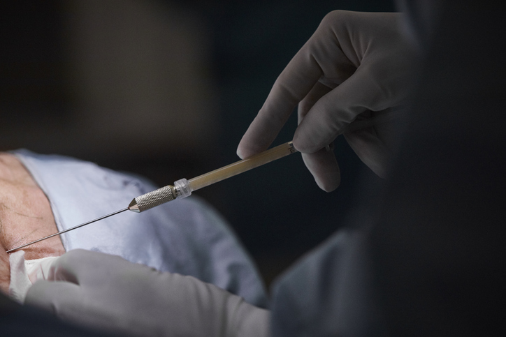 Hands of female surgeon injecting patient in dark