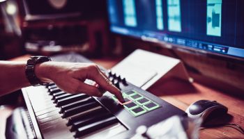 Producer Creating New Beats With MIDI Keyboard In Studio