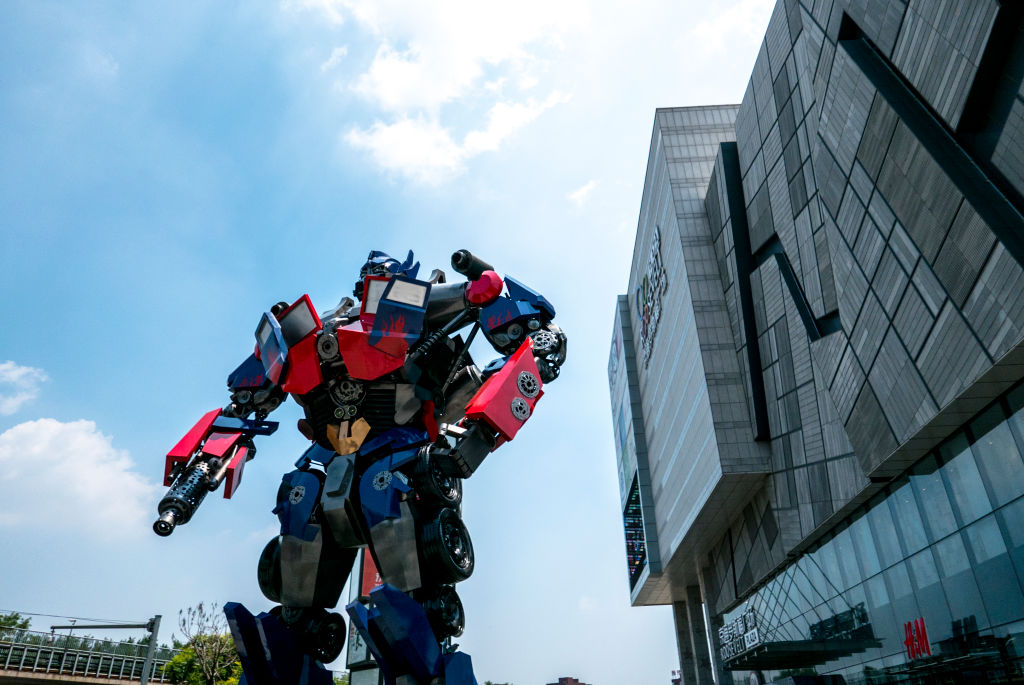 A huge Optimus Prime stands on a plaza in front of a...