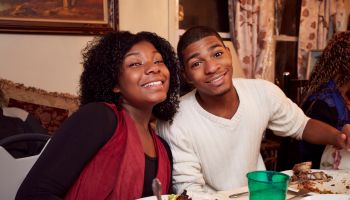 Smiling Black brother and sister at dinner table