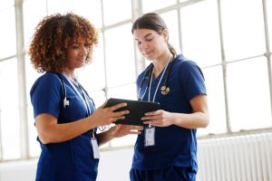 Two healthcare professionals in conversation, looking at digital tablet