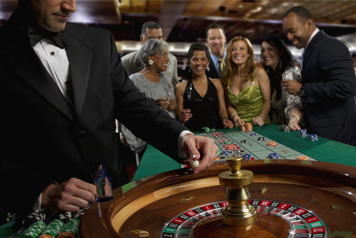 Excited friends gambling at roulette table in casino