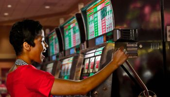 Mixed race woman playing slot machines in casino