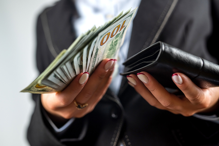 Close-up of female hands putting a dollar bill in her purse.