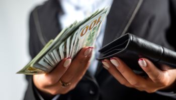 Close-up of female hands putting a dollar bill in her purse.