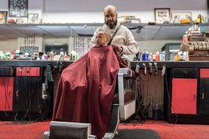 Black customers receive a haircut from barbers at a Black owned Barbershop