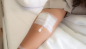 Blurry image of the doctor puts intravenous injection on the patient's arm for drip medicine and collect blood samples.