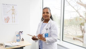 Confident professional senior female doctor looks up from patient chart