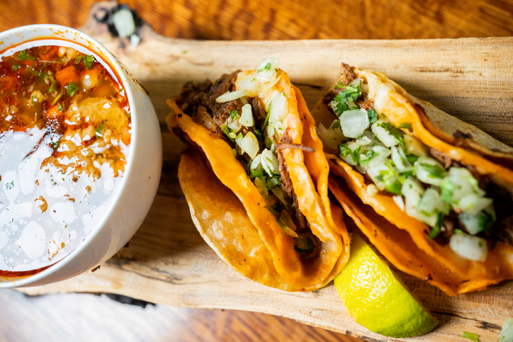 Street tacos - filled with savory and juicy birria or carne asada, topped with onions, cilantro, and spicy salsa, all nestled in a warm corn tortilla