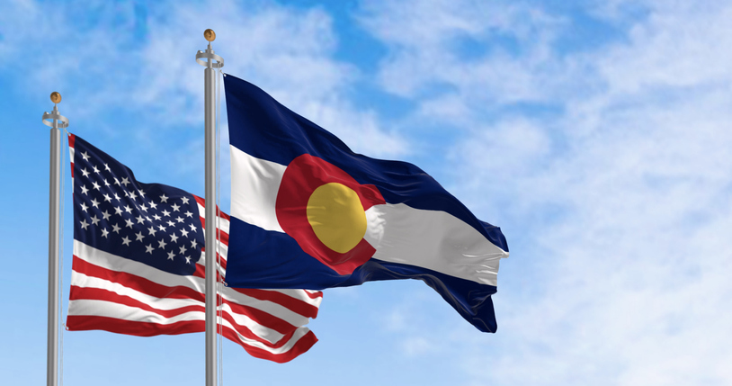 The Colorado state flag waving with the national flag of the US on a clear day
