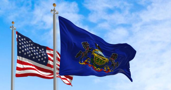 Pennsylvania state flag waving alongside the national flag of the United States on a sunny day