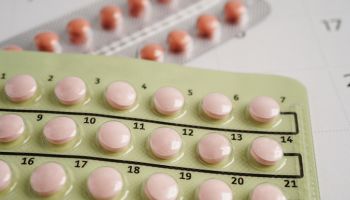 Pregnancy test with birth control pills for female on calendar, ovulation day.