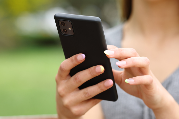 Woman hands close up using smart phone in a park