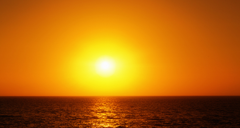 Beautiful orange sunset in clear sky reflected in a gently rippled ocean