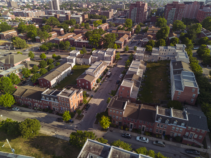 Affordable housing in Jonestown neighborhood. Brick row houses in sunlight in Baltimore, MD. Aerial view of streets with cars and rooftops