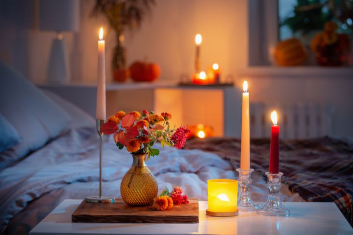 autumnal chrysanthemum in vase with burning candles in bedroom